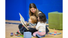 Photo of early childhood educator reading to two children