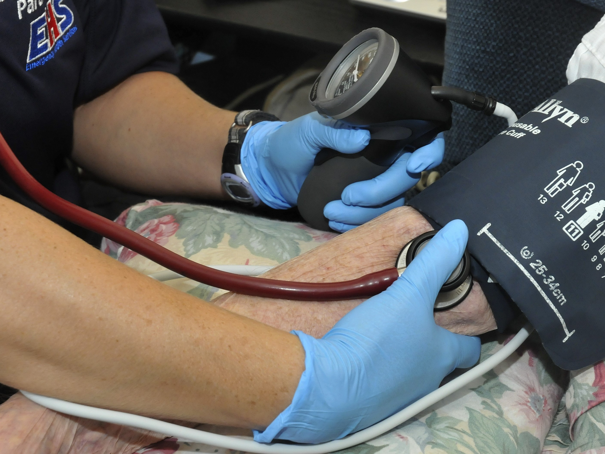 Photo showing the hands of a paramedic taking a patient's blood pressure