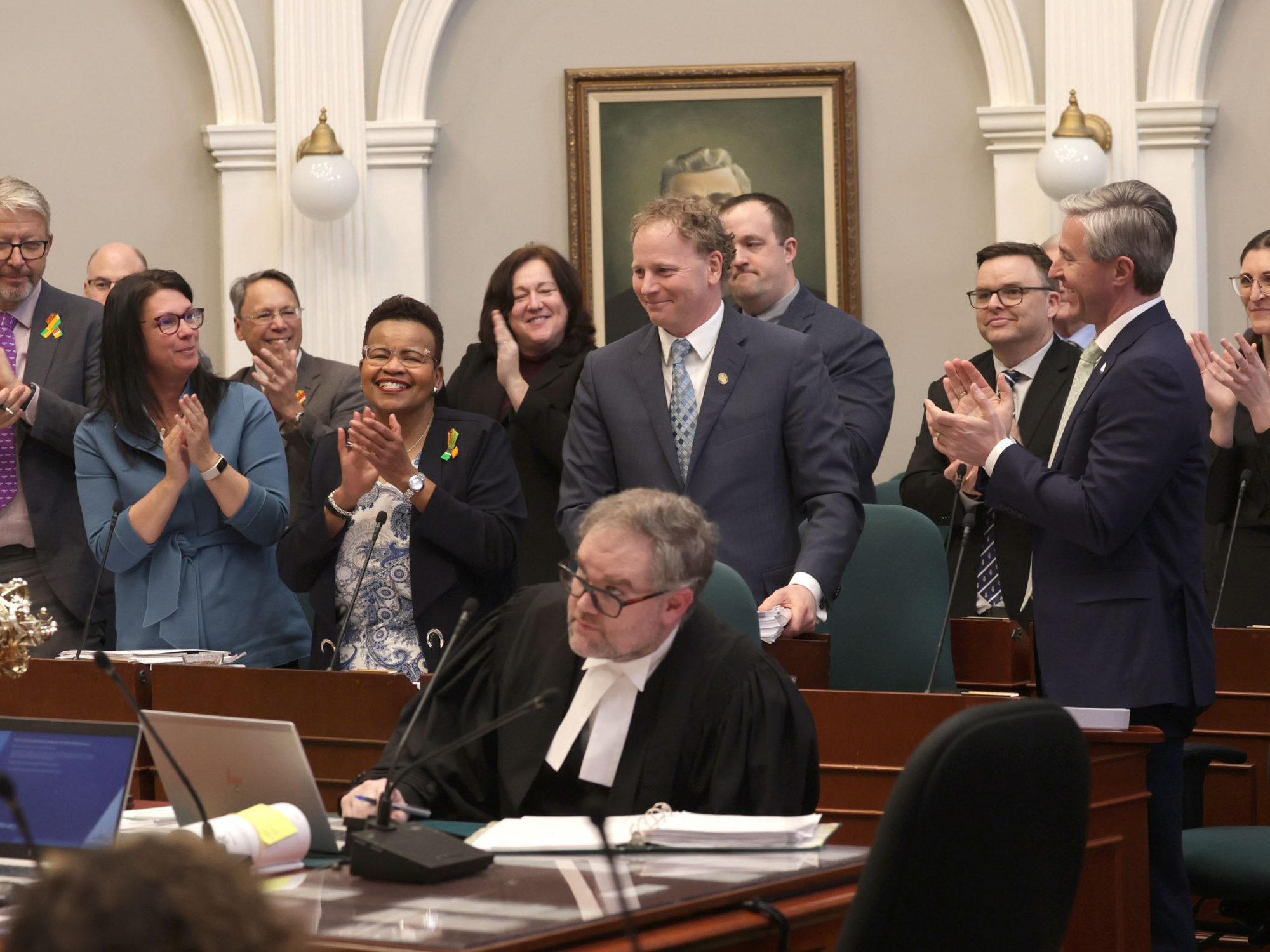 Photo of government MLAs applauding Finance and Treasury Board Minister Allan MacMaster in the legislature