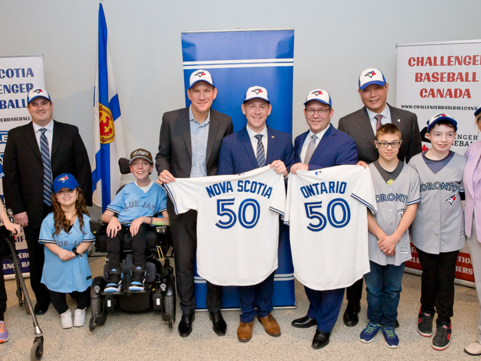 Young athletes from the Jays Cares Challenger Baseball program with (L-R): Randy Crouse, Challenger Baseball National Coordinator; James Dodds, Chair, Jays Cares Foundation; Colton LeBlanc, Minister of Service Nova Scotia; Doug Downey, Ontario Attorney General; Stan Cho, Ontario Minister of Long-Term Care; and Barbara Adams, Minister of Seniors and Long Term Care for Nova Scotia