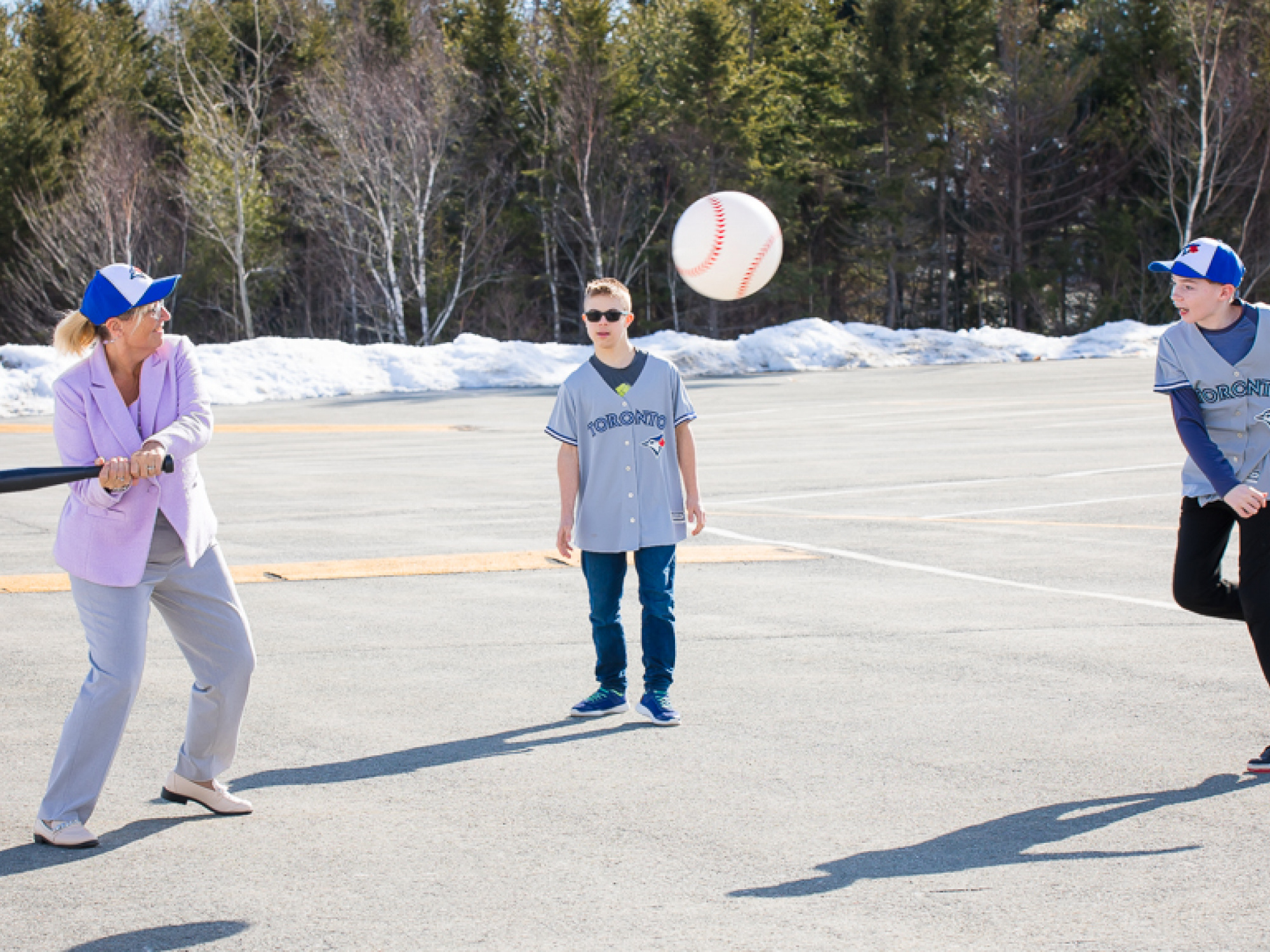 Barbara Adams, Minister of Seniors and Long Term Care, swings a baseball bat at an inflatable baseball thrown by a young athlete from the Jays Care’s Challenger Baseball program. (Communications Nova Scotia)