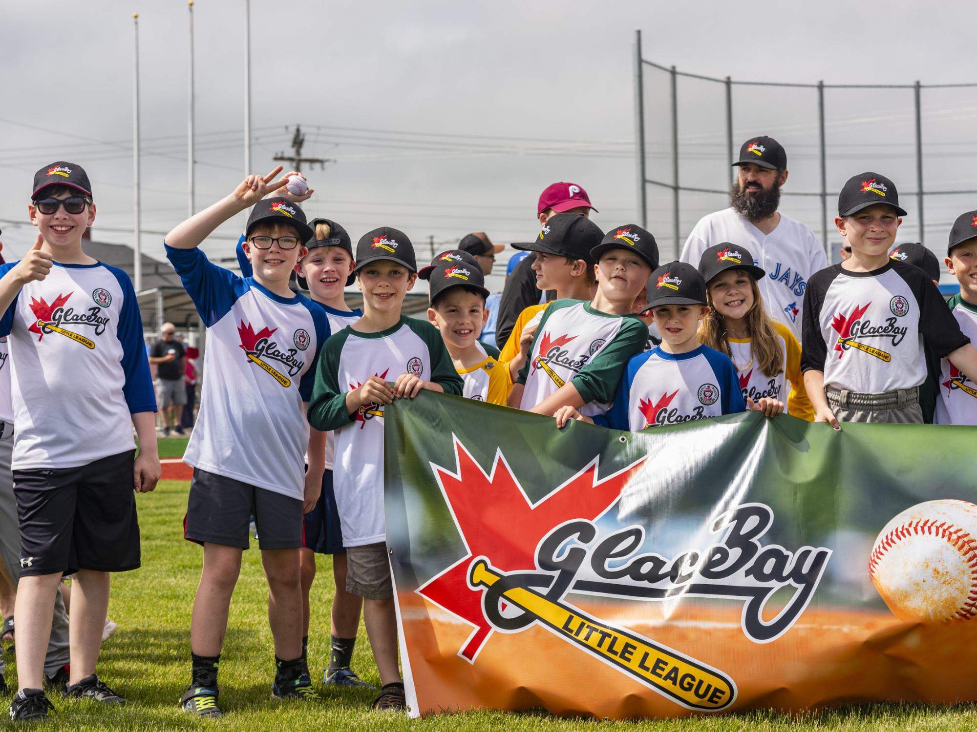 Photo of children wearing ball caps and Glace Bay team uniforms and holding banner that says Glace Bay Little League
