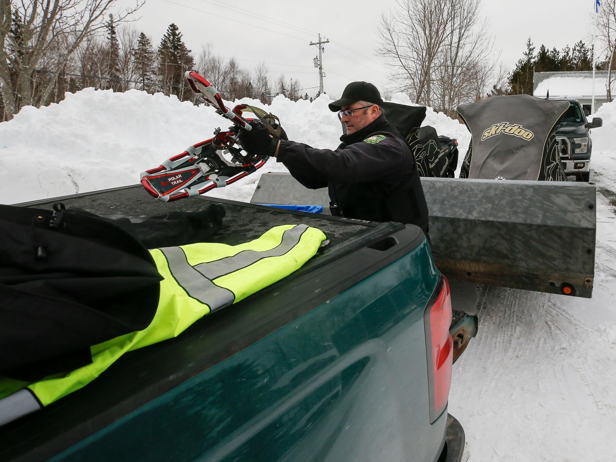 Photo of a conservation officer putting snowshoes on the back of a truck