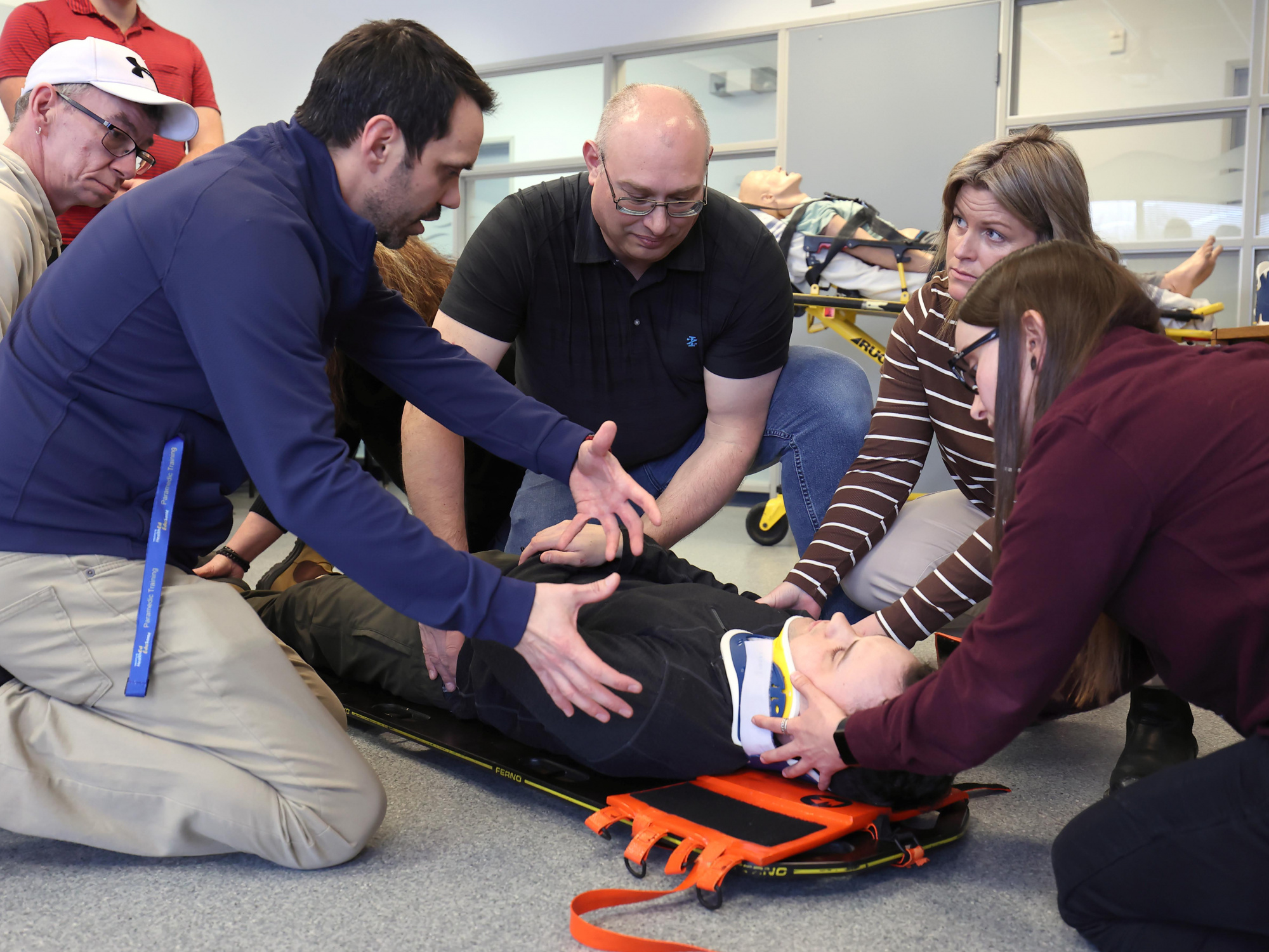 Instructor Mike Miller teaches the learners in the Emergency Medical Responder program how to secure a patient to a spine board