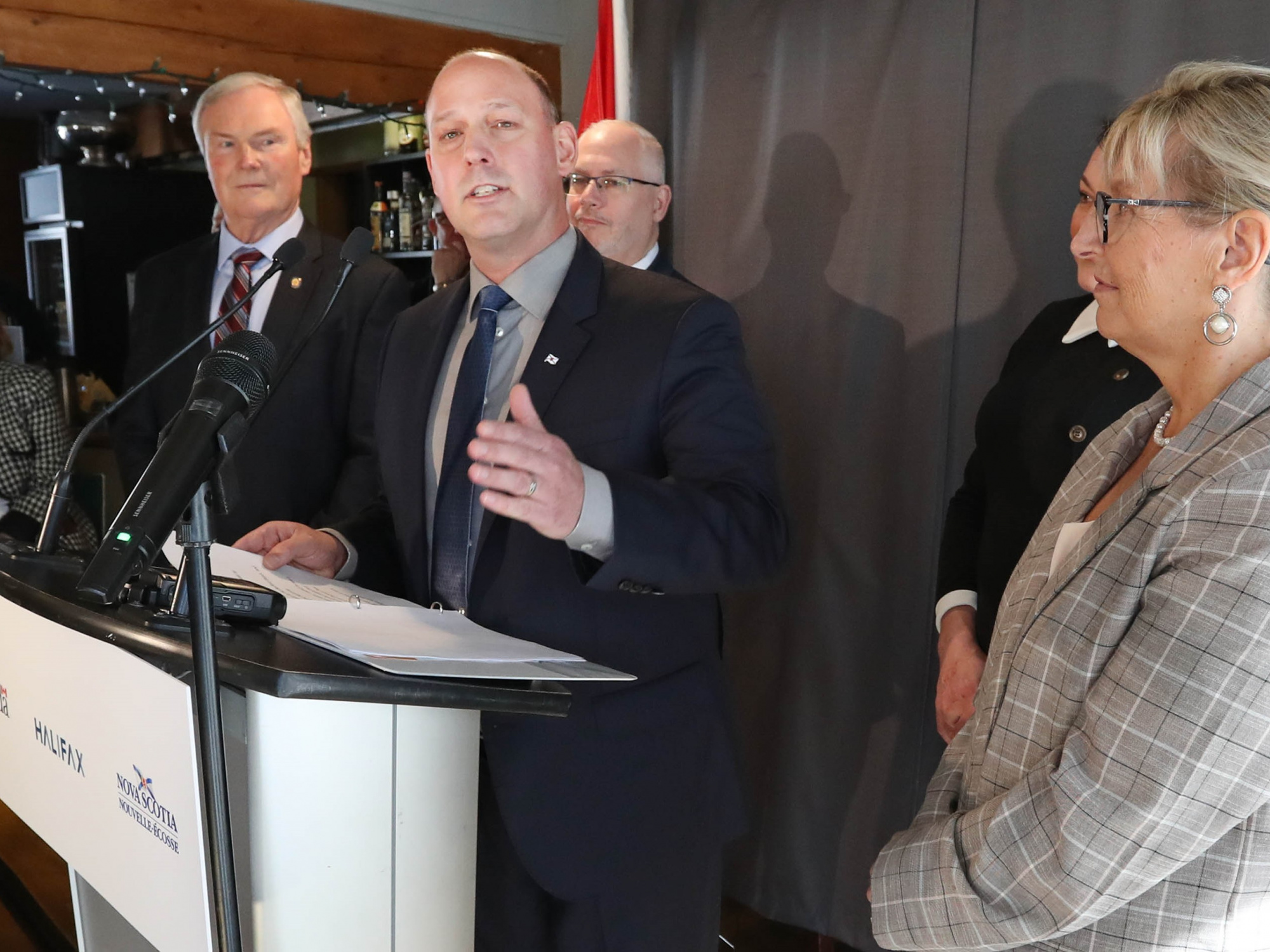 Environment and Climate Change Minister Timothy Halman at a podium, flanked by other provincial cabinet ministers