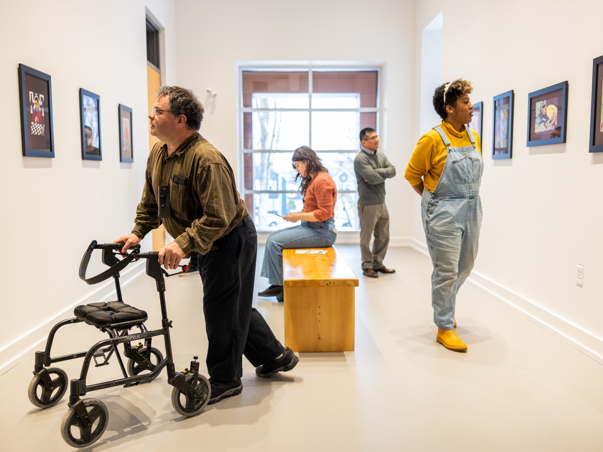 Photo of people, including a person using a walker, looking at art in a gallery setting