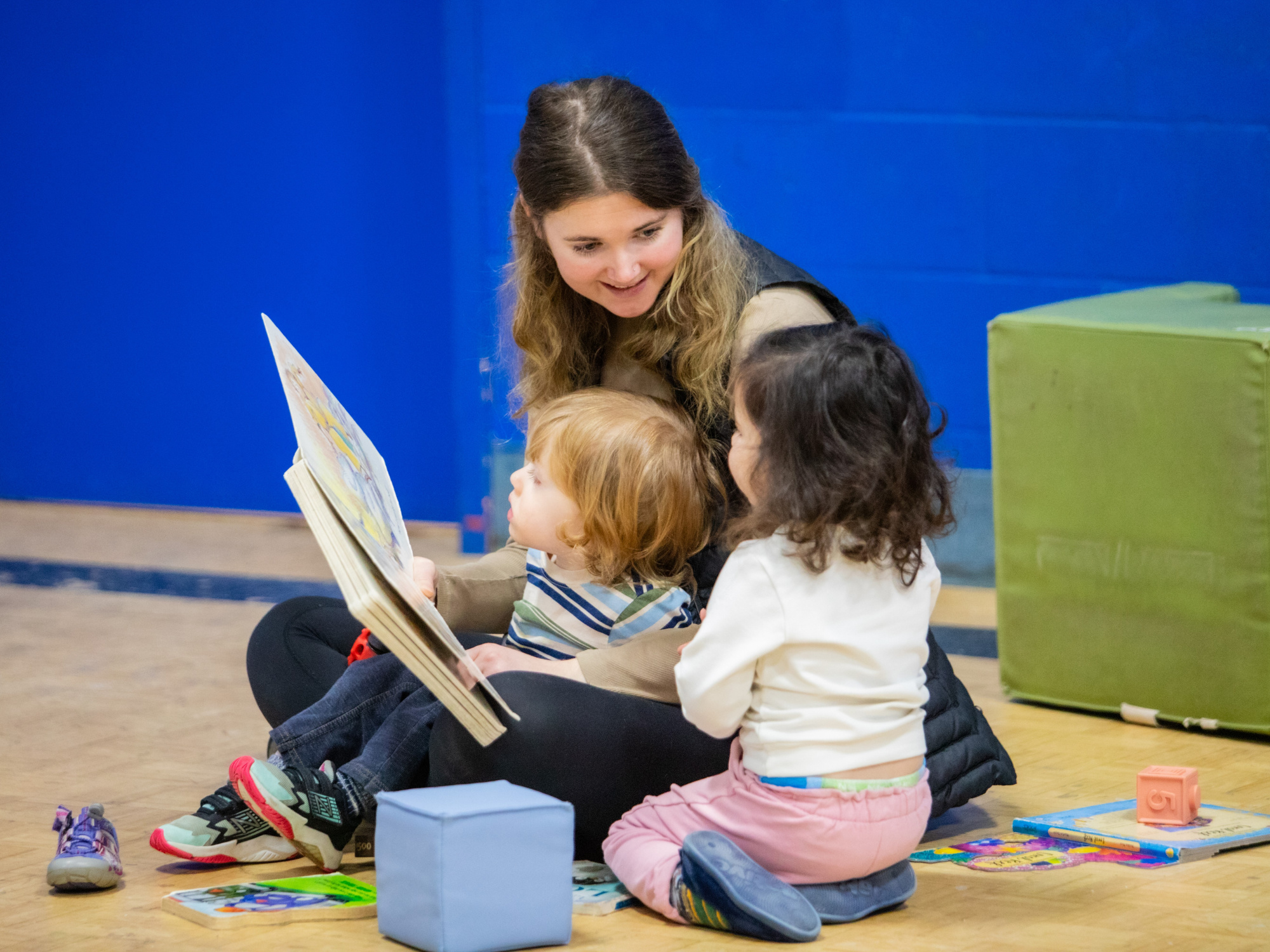 Photo of early childhood educator reading to two children