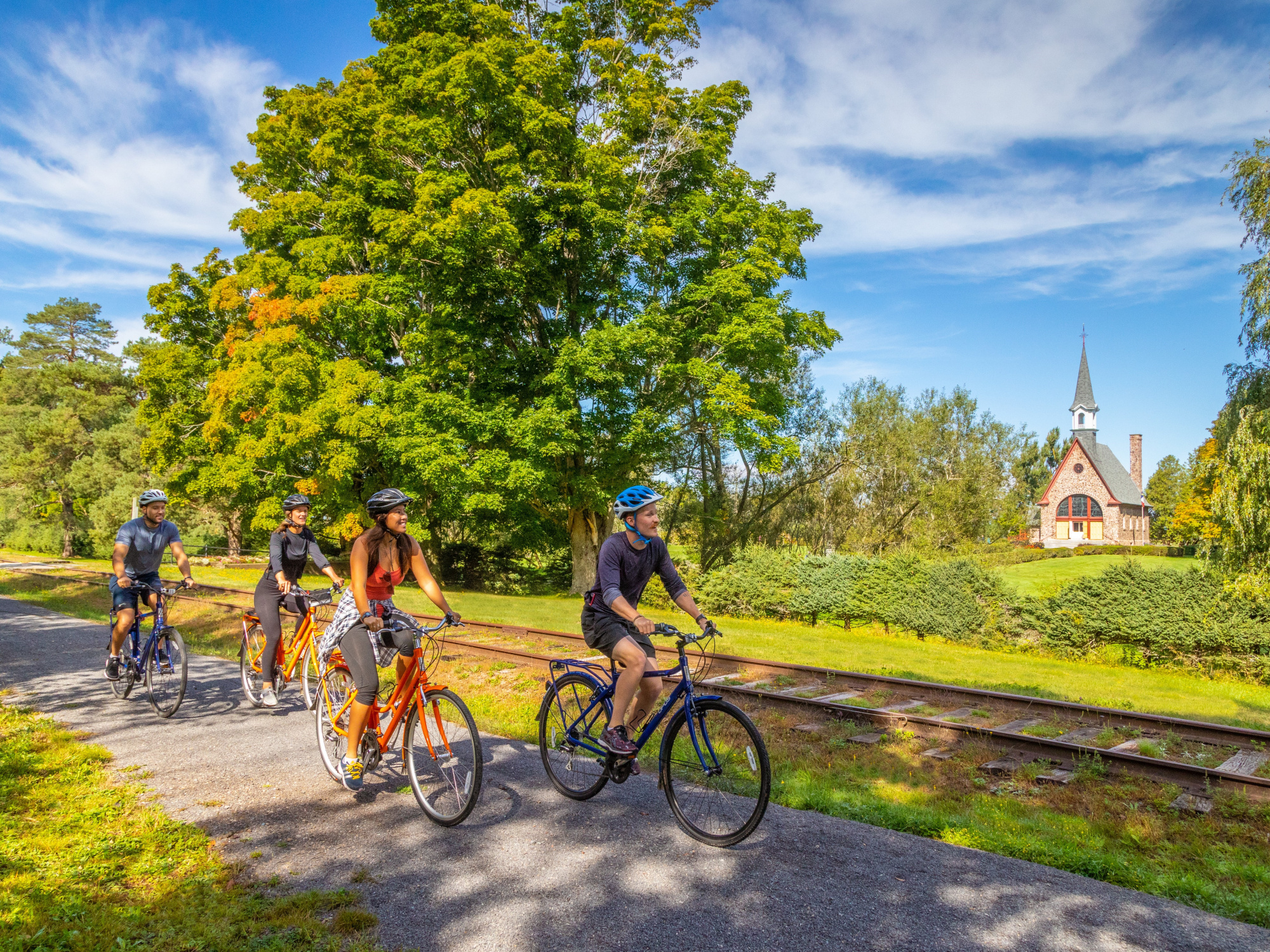 Photo of four people on bicycles on a trail and a church in the background