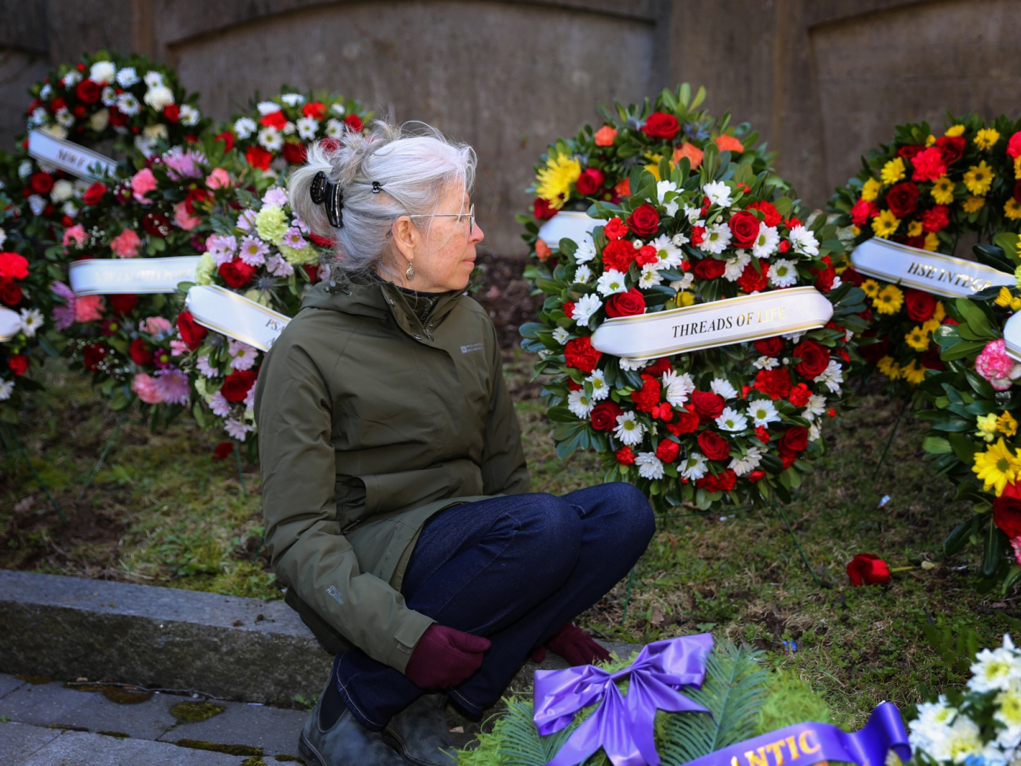 Candace Palumbo of Threads of Life, a support and advocacy organization, sits in front of wreaths placed outside Province House during the 2023 Day of Mourning ceremony. Her husband, Tony, died at age 59 from asbestos-related mesothelioma. (Communications Nova Scotia / File)