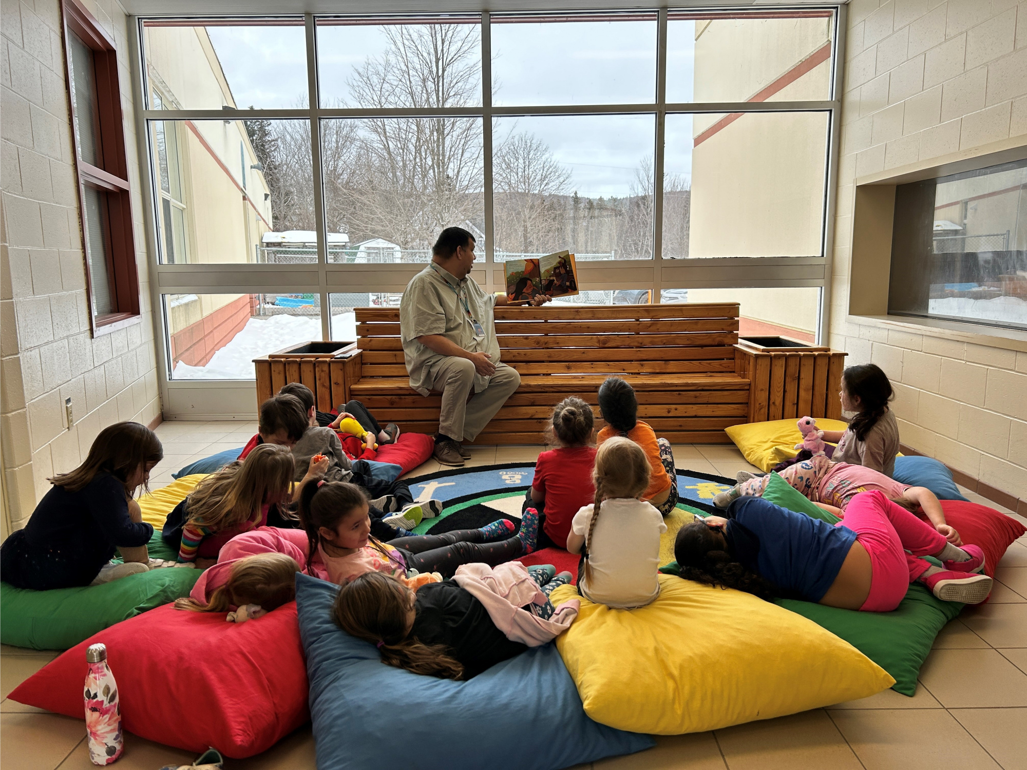 Photo of Phillip Prosper, a Mi’kmaw support teacher at Whycocomagh Education Centre in Cape Breton, reading to Grade Primary students