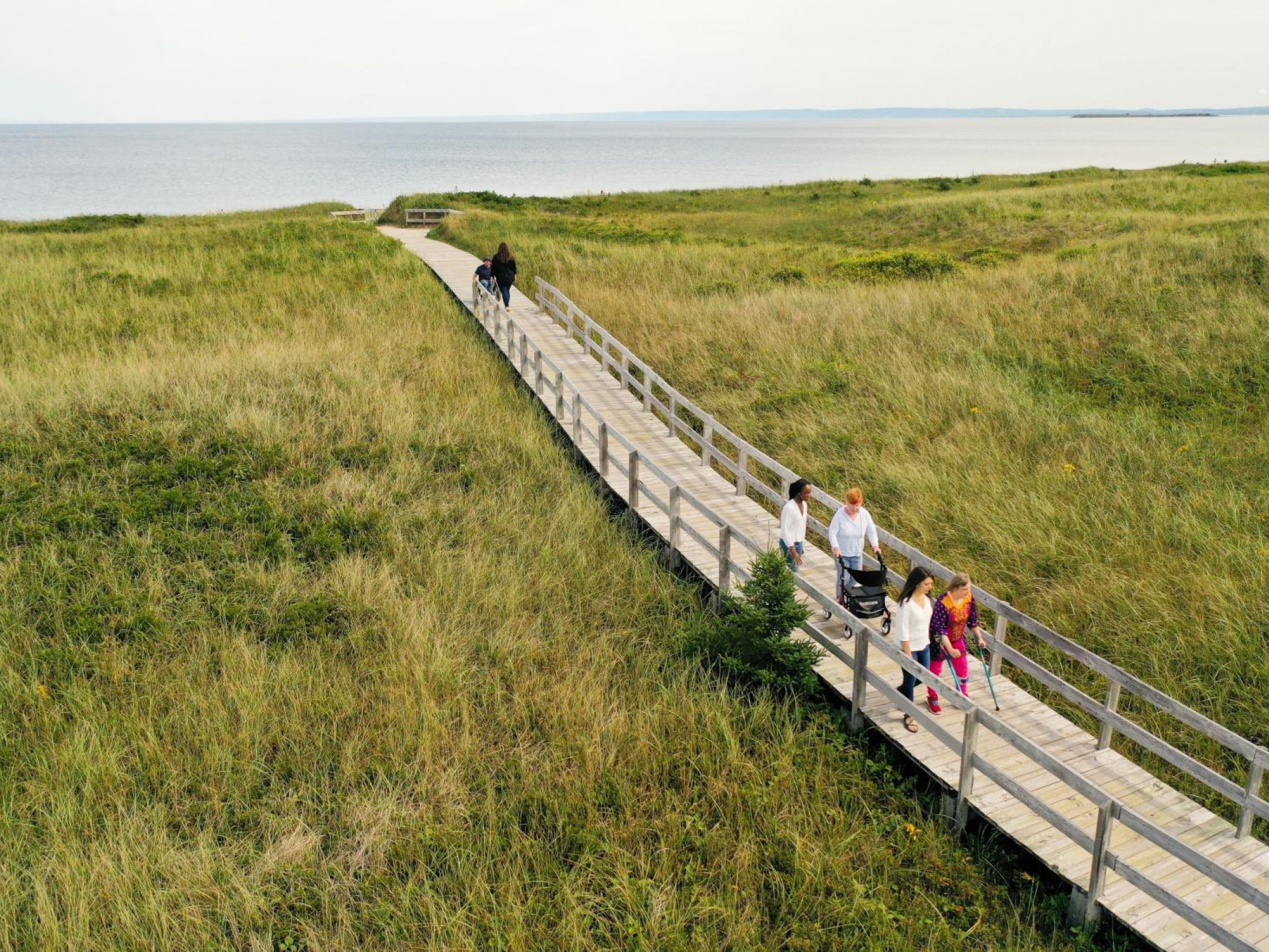 Photo of people walking on a boardwalk to a beach