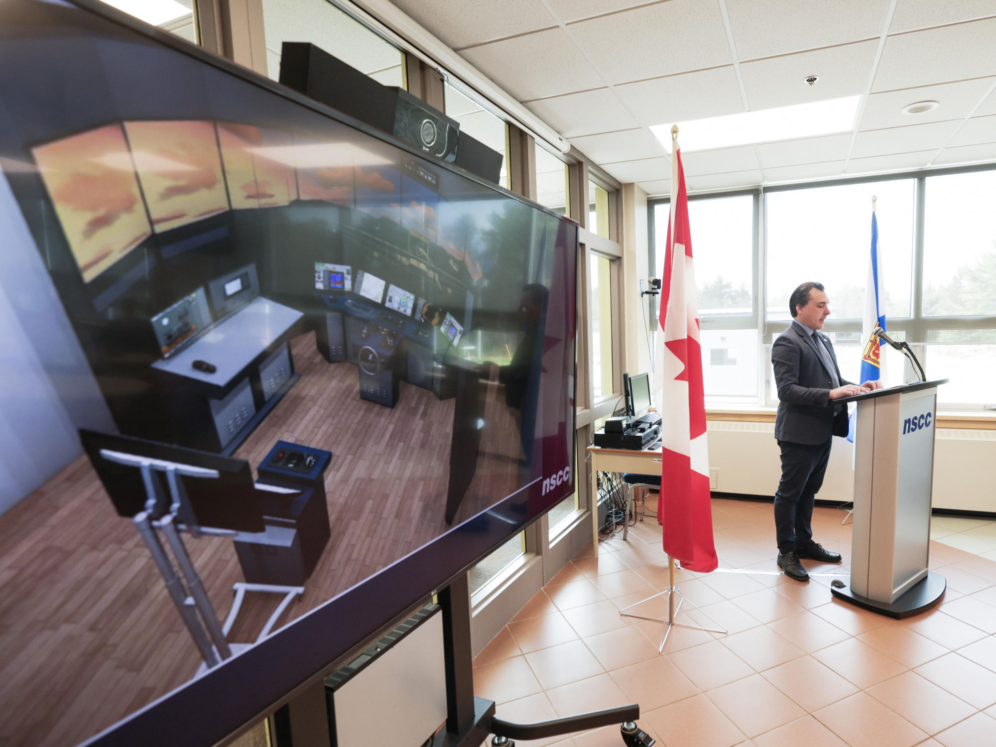 Photo of fisheries simulator on a screen and Shelburne MLA Nolan Young at a podium in the background