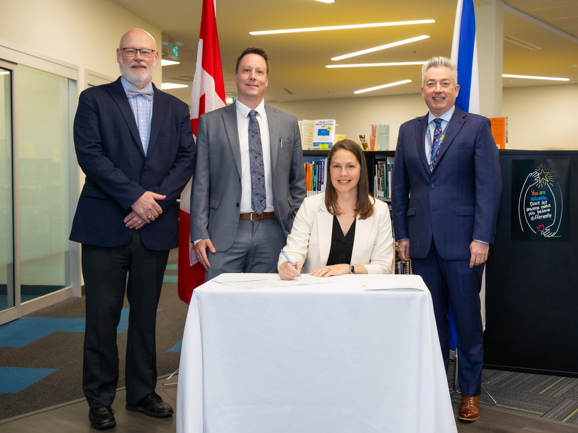 Photo of Education and Early Childhood Development Minister Becky Druhan at a small table and three officials around her