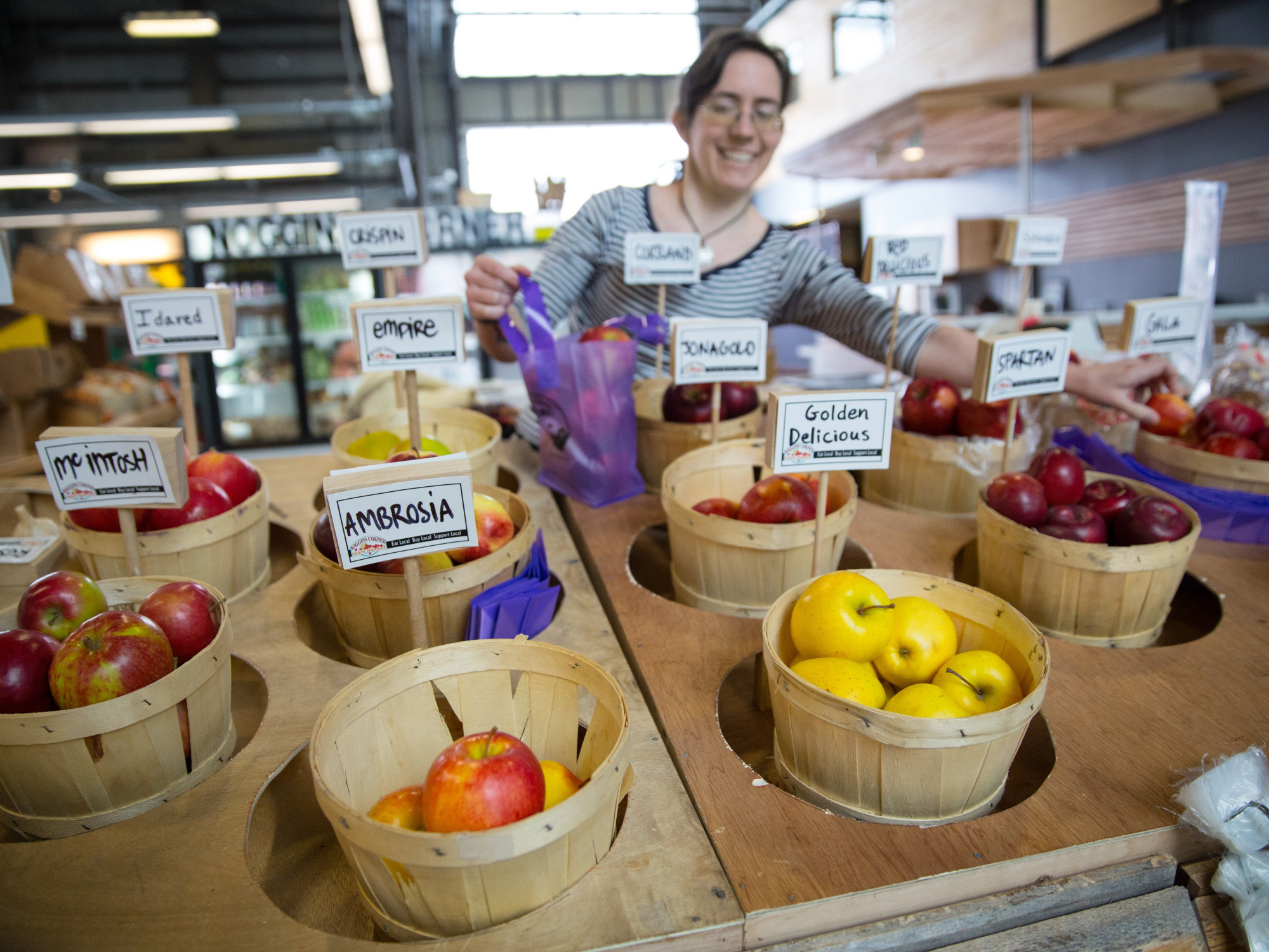 Photo of vendor and baskets of apples at a farmers' market