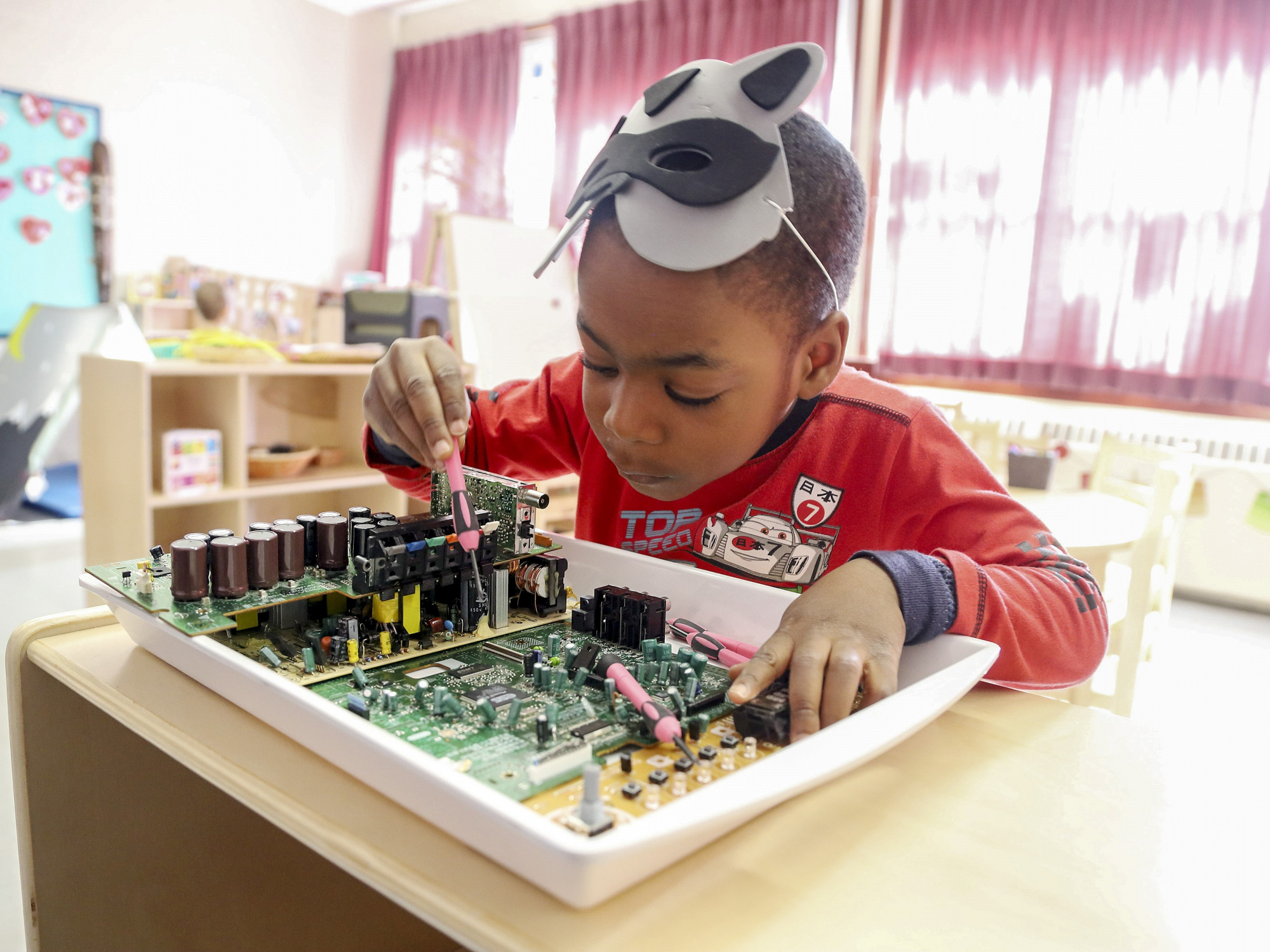 Photo of a child with a circuit board in a classroom