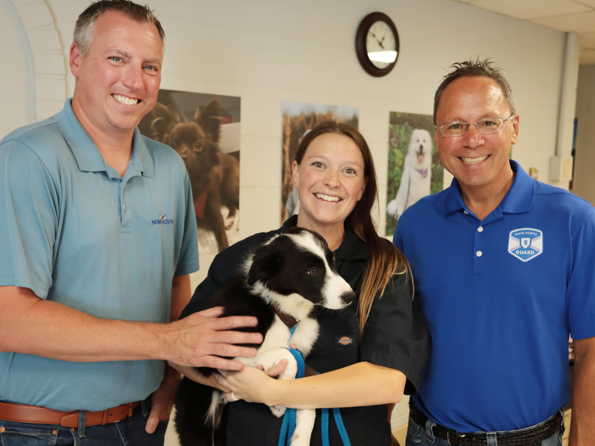 Photo of Agriculture Minister Greg Morrow, Advanced Education Minister Brian Wong and Dr. Laura Wilson, who's holding a border collie