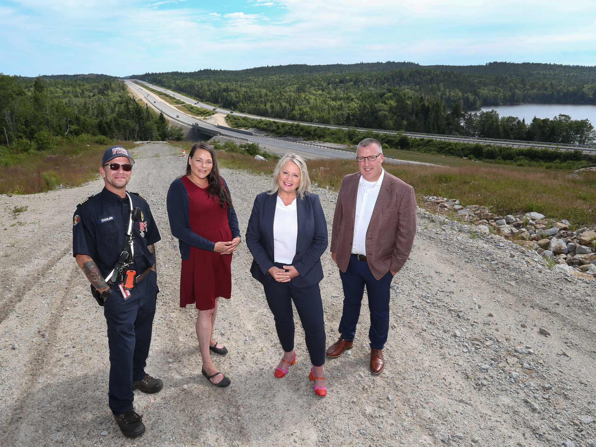 Photo of Public Works Minister Kim Masland and three other people with Highway 103 in the background