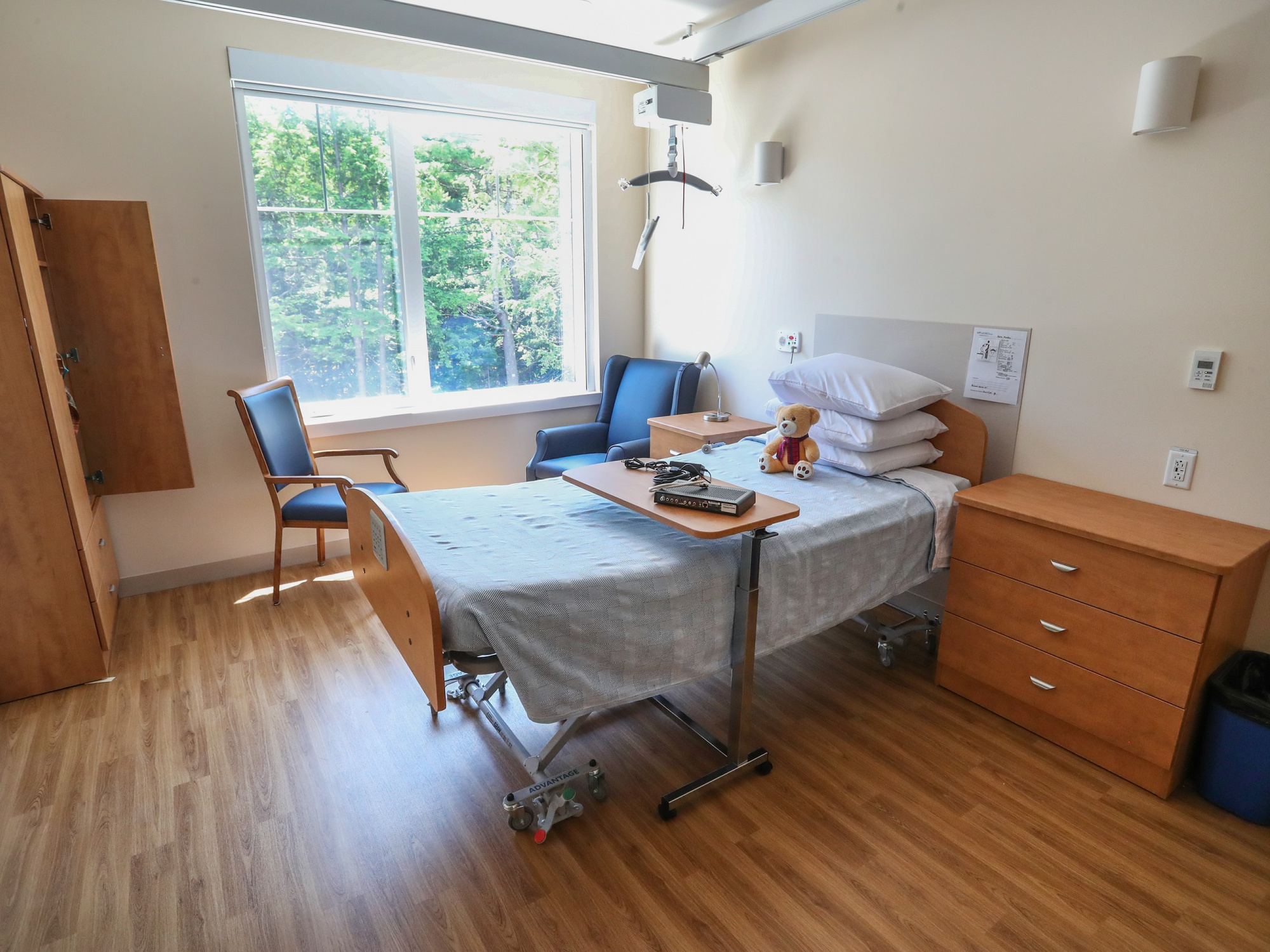 Photo of resident's room at Mahone Bay Nursing Home, including bed, bedside table and chairs