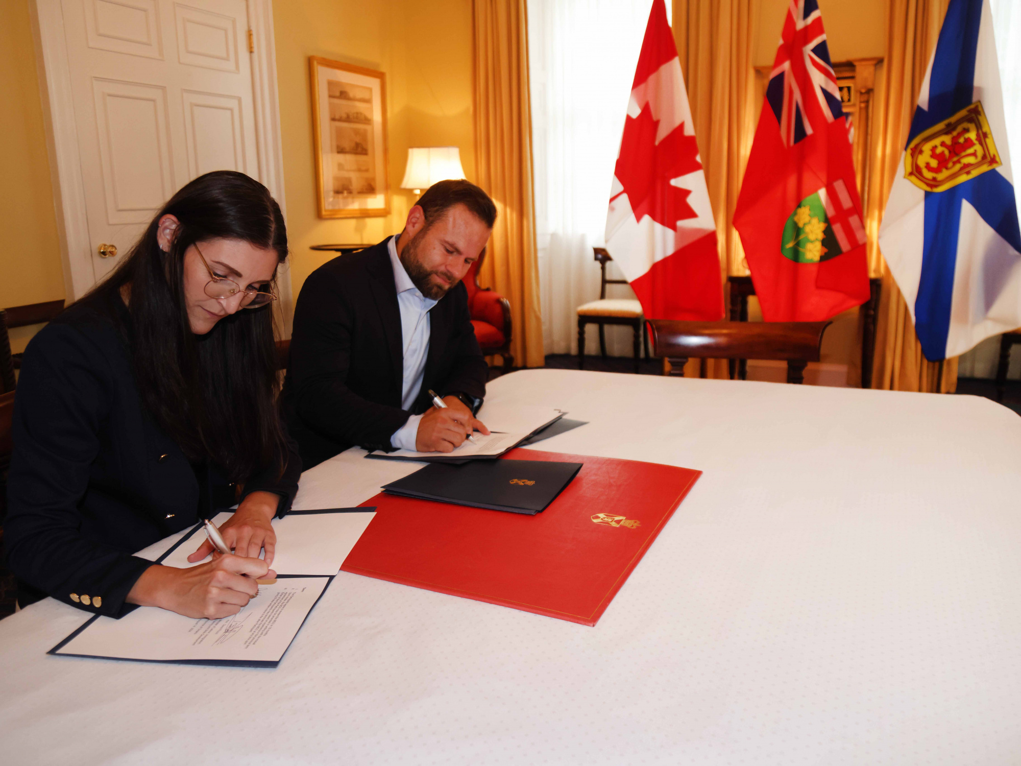 Jill Balser, Minister of Labour, Skills and Immigration, and David Piccini, Minister of Labour, Immigration, Training and Skills Development for the Province of Ontario, sign a memorandum of understanding detailing collaboration between the two provinces to improve recognition of international credentials for skilled trades professionals. 