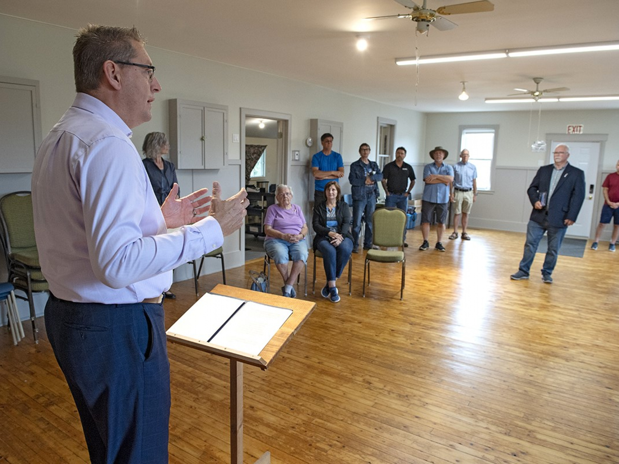 Photo of MLA Chris Palmer at a short podium speaking to people in a community hall