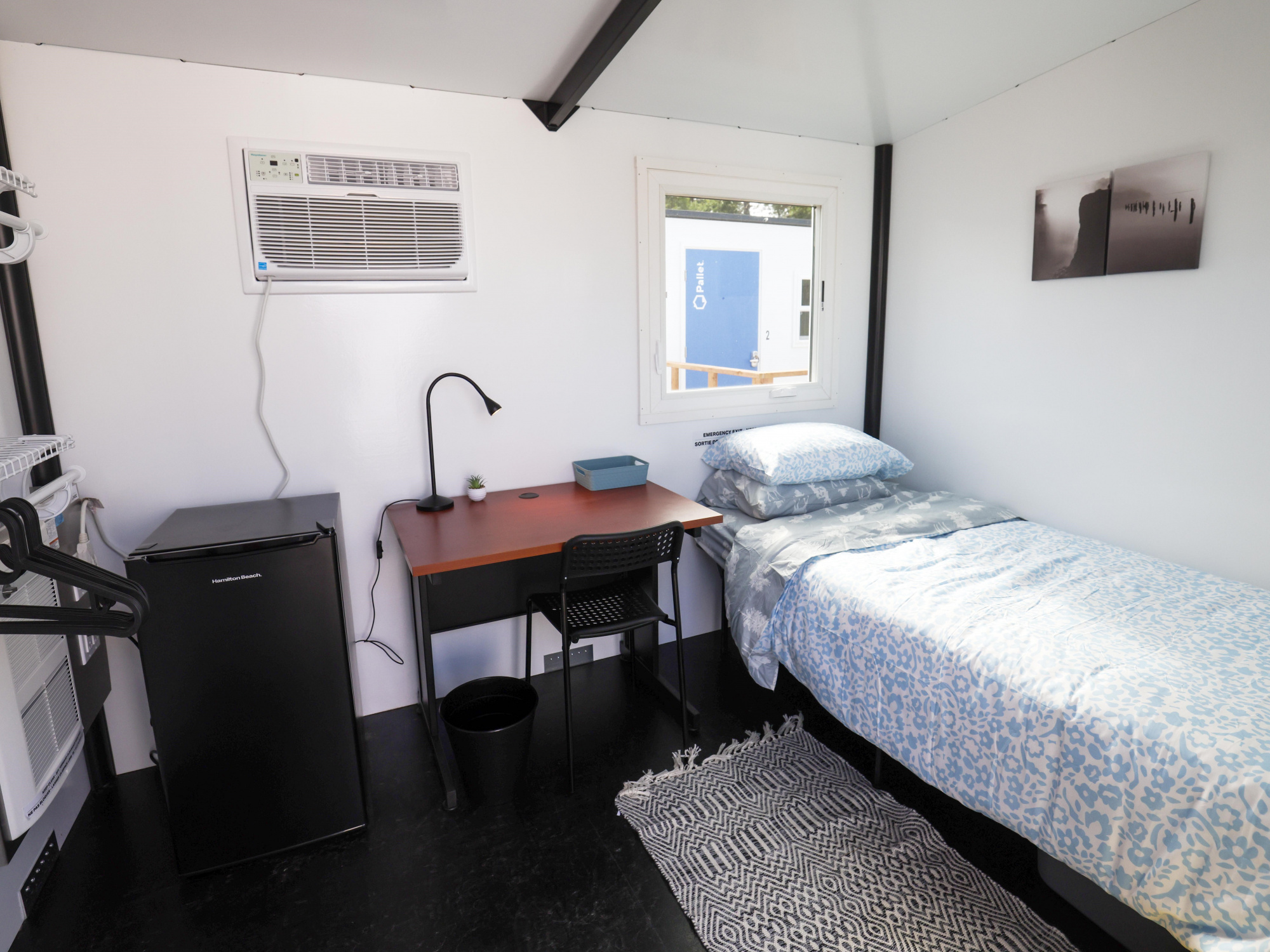 Photo of interior of Pallet shelter with bed, mini fridge and table