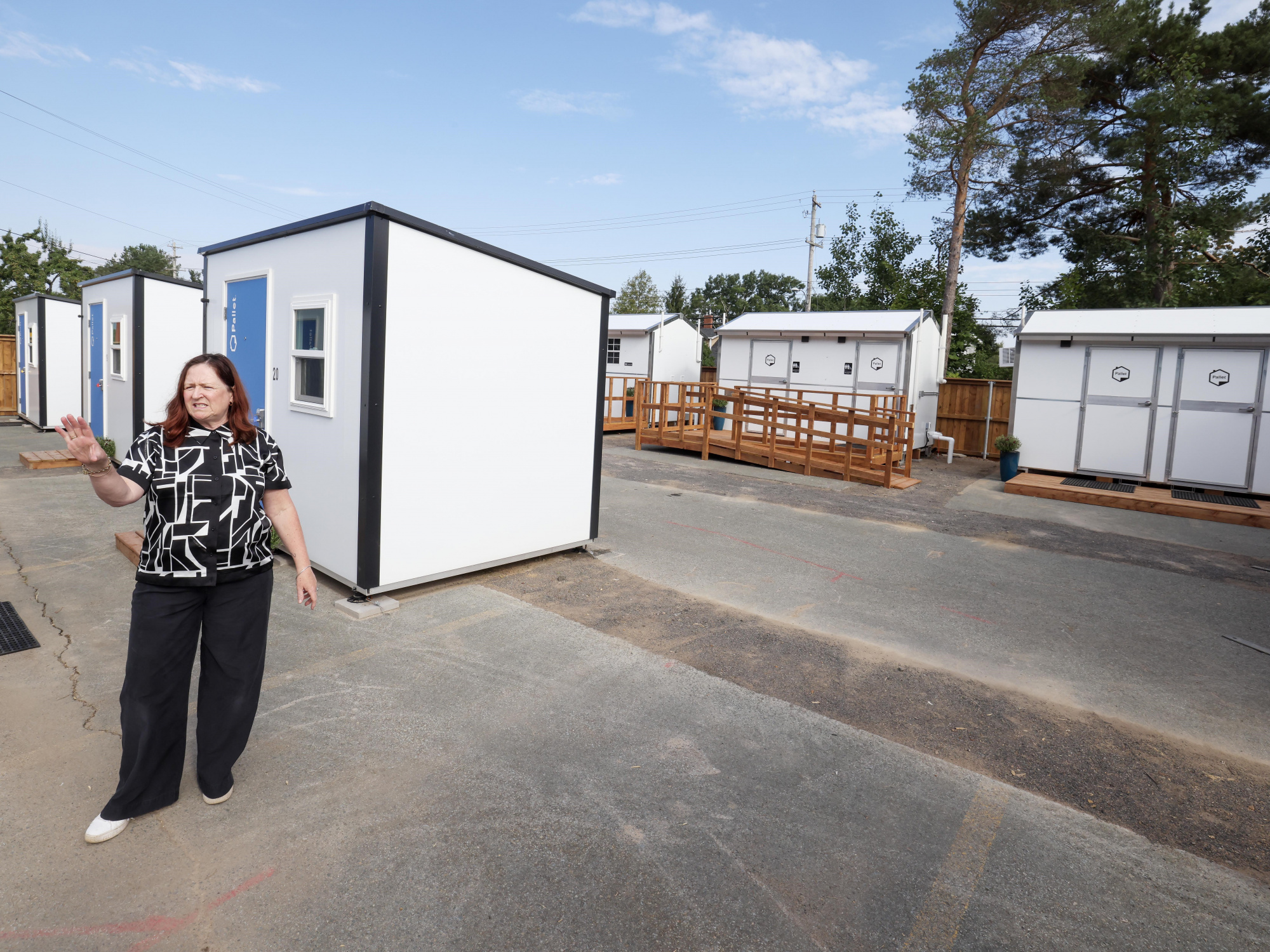 Photo of woman standing outside a Pallet shelter