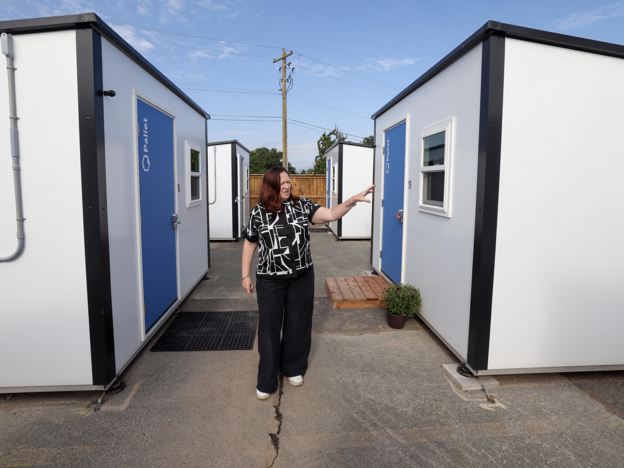 Photo of a woman standing between Pallet shelters