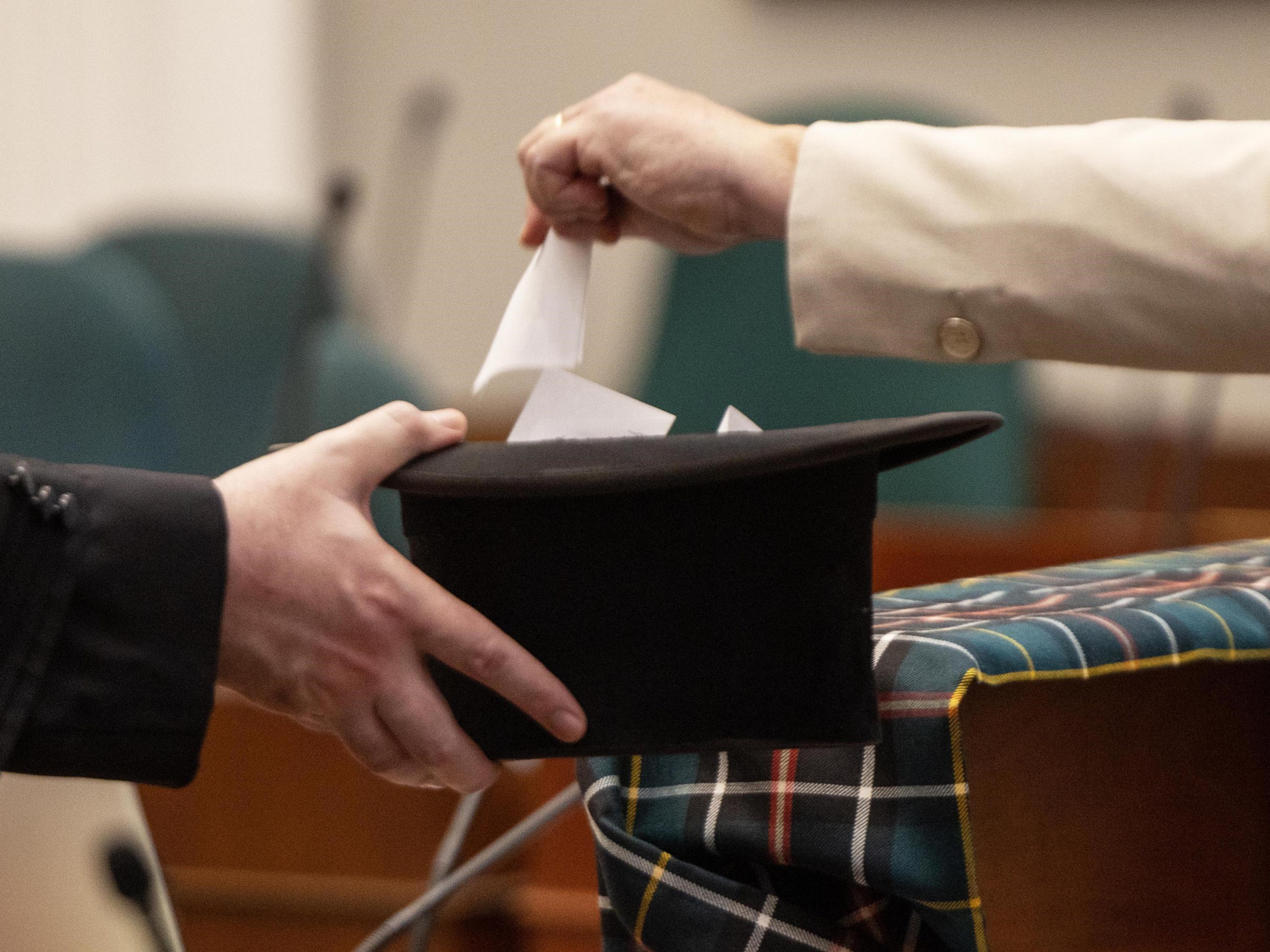 Photo of someone dropping a ballot in a hat