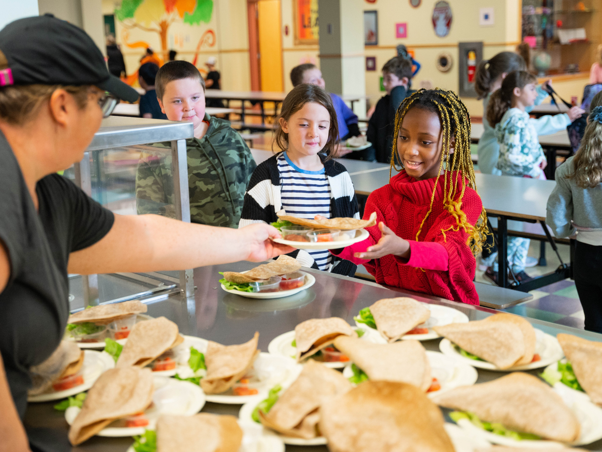 Photo of school lunch worker serving a pita to a student