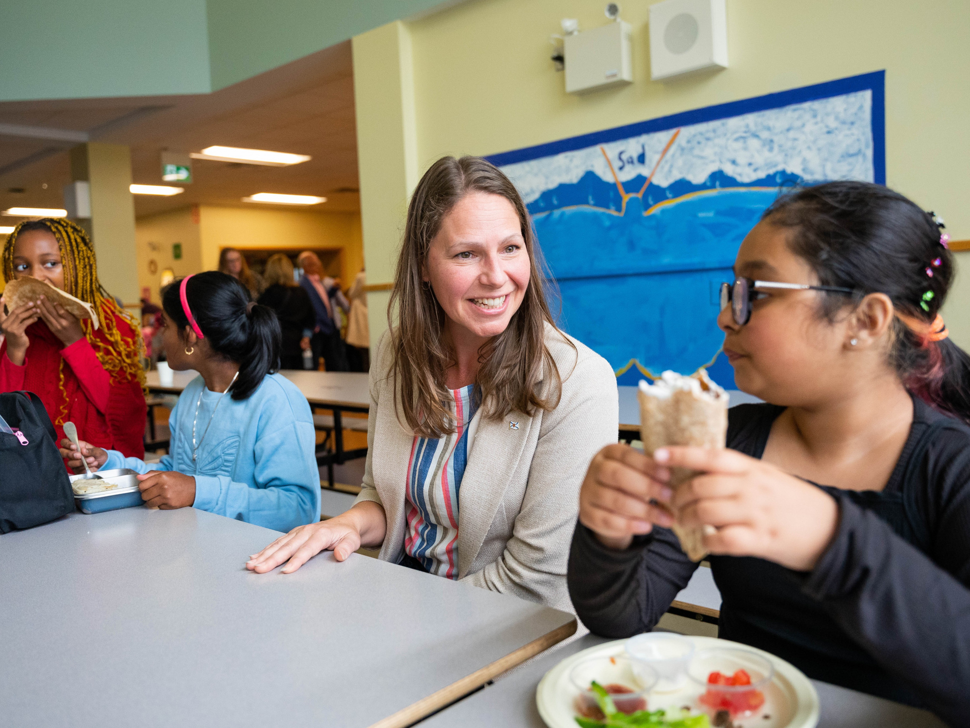 Photo of Education and Early Childhood Development Minister Becky Druhan with children at lunchtime