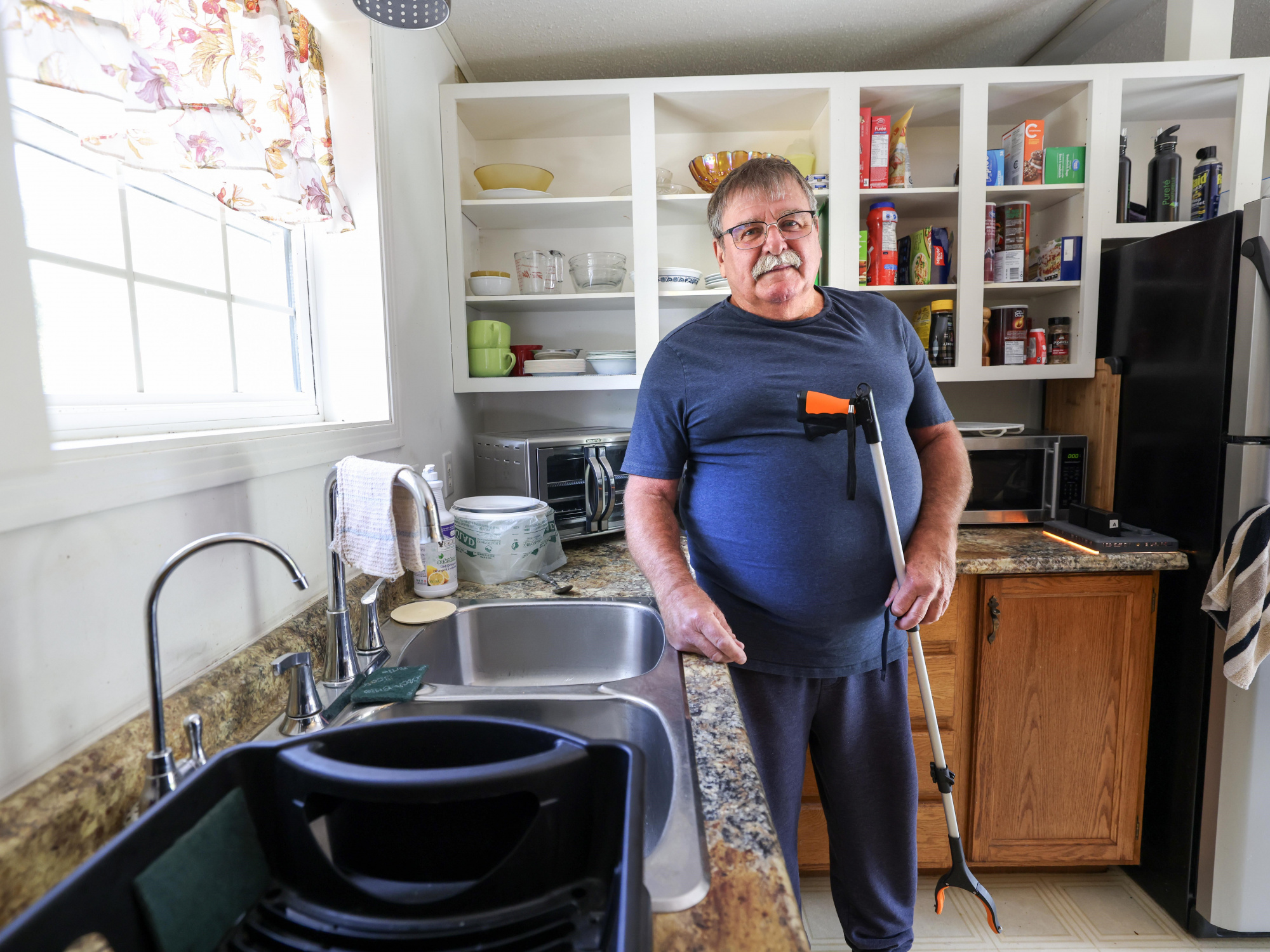 Photo of a man in a kitchen holding a grabber