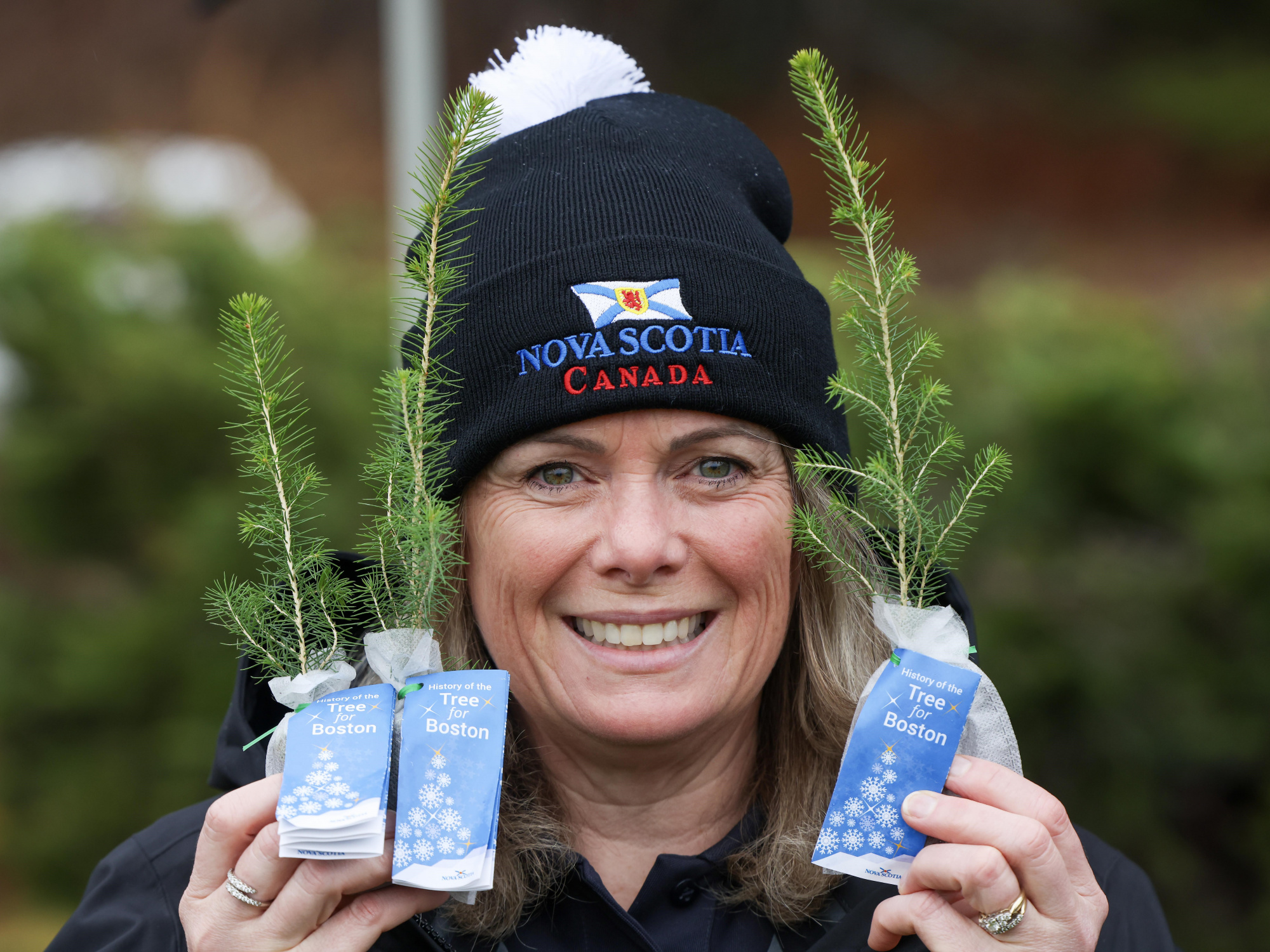 Photo of a woman holding seedlings on either side of her face