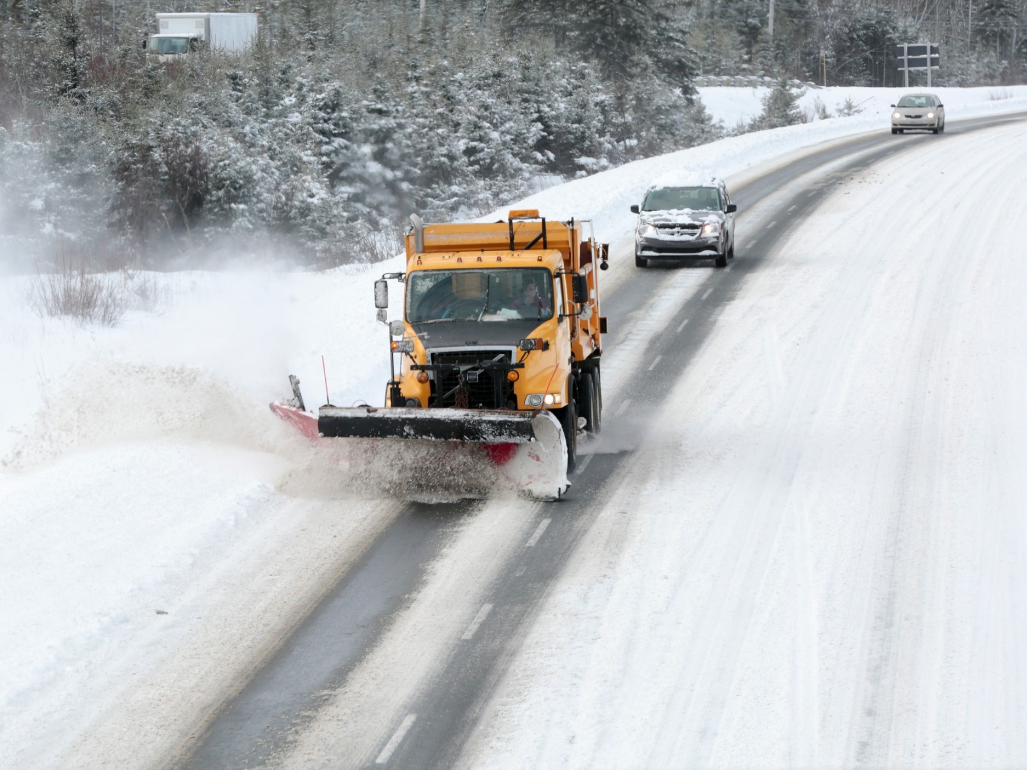 A yellow snowplow truck clears the road.