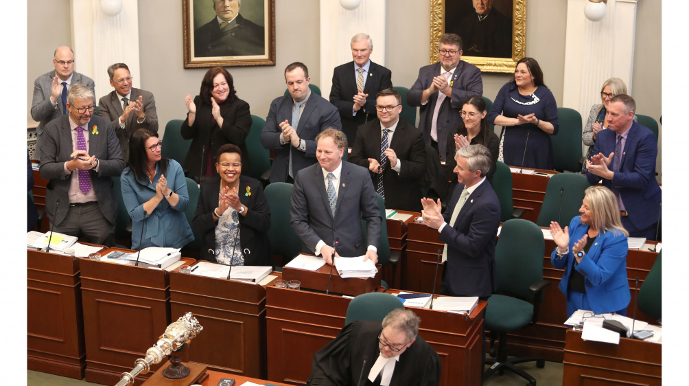 Photo of government MLAs applauding Finance and Treasury Board Minister Allan MacMaster in the legislature