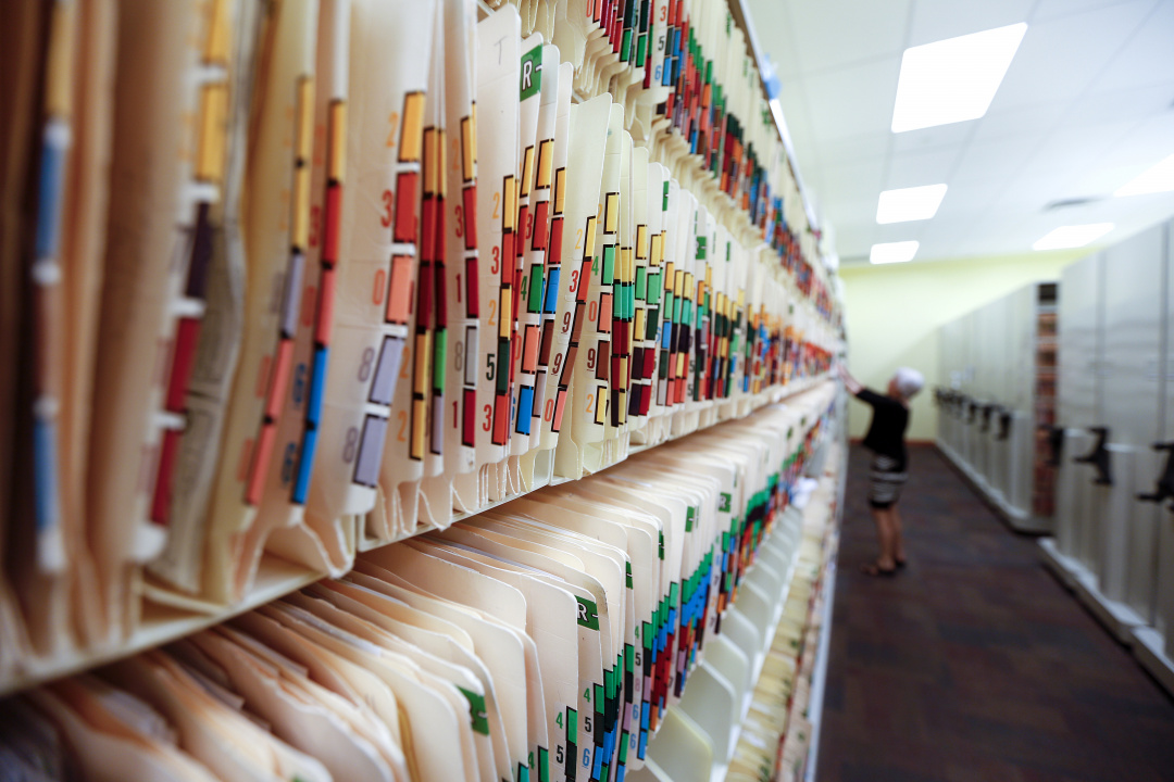 Photo showing rows of file folders with a staff person in the background