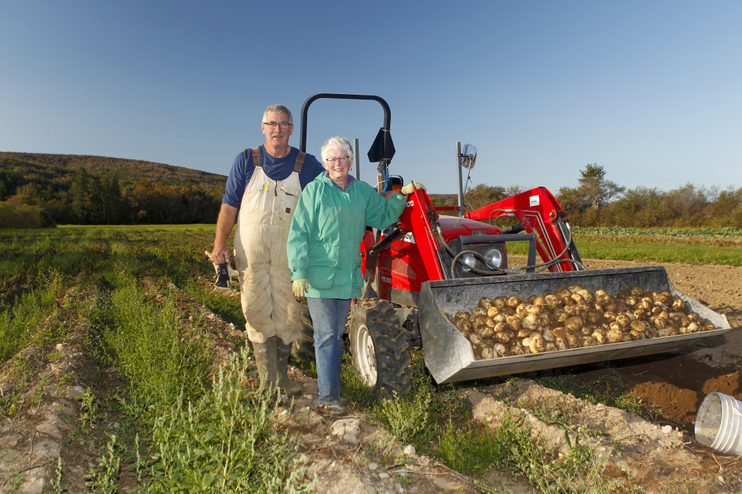 Photo of two farmers standing beside a tractor in a field.