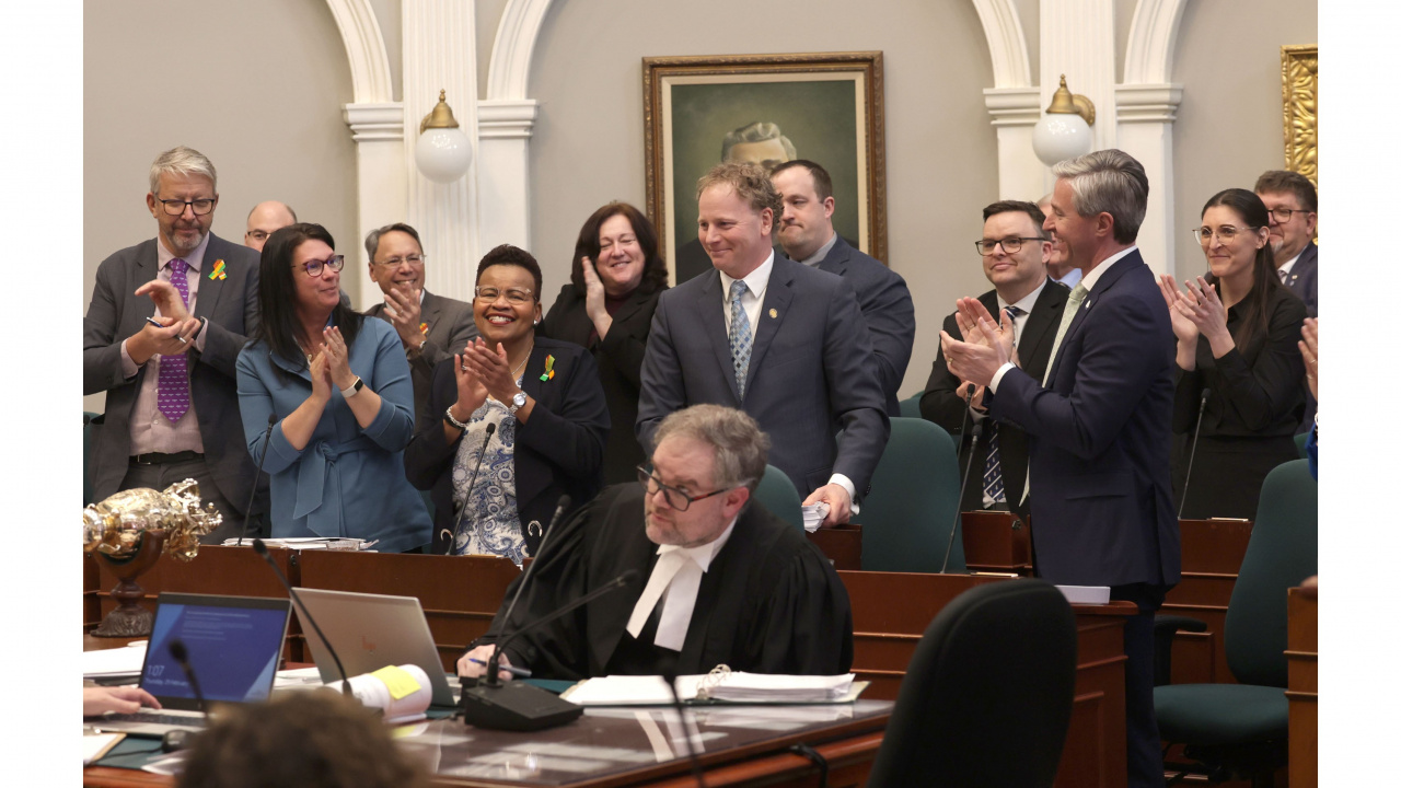 Photo of government MLAs applauding Finance and Treasury Board Minister Allan MacMaster in the legislature