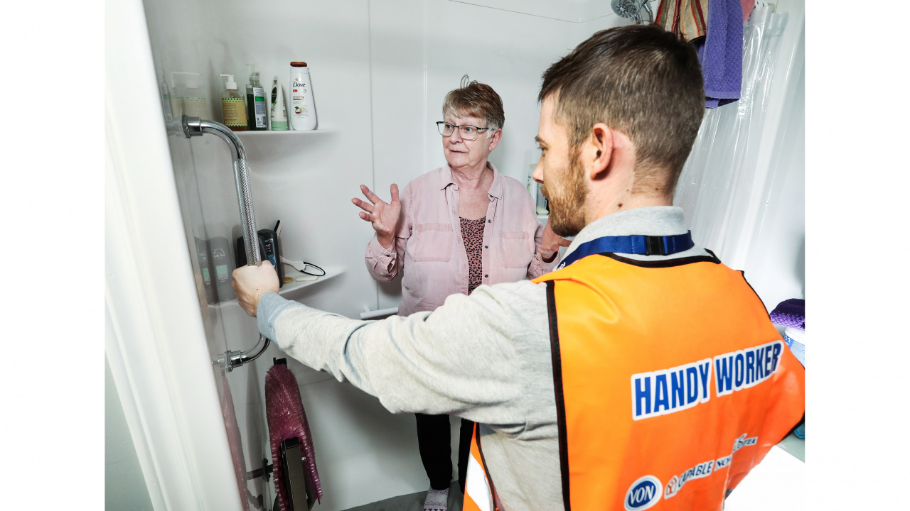 Photo of handyman talking to a senior in a bathroom about improvements