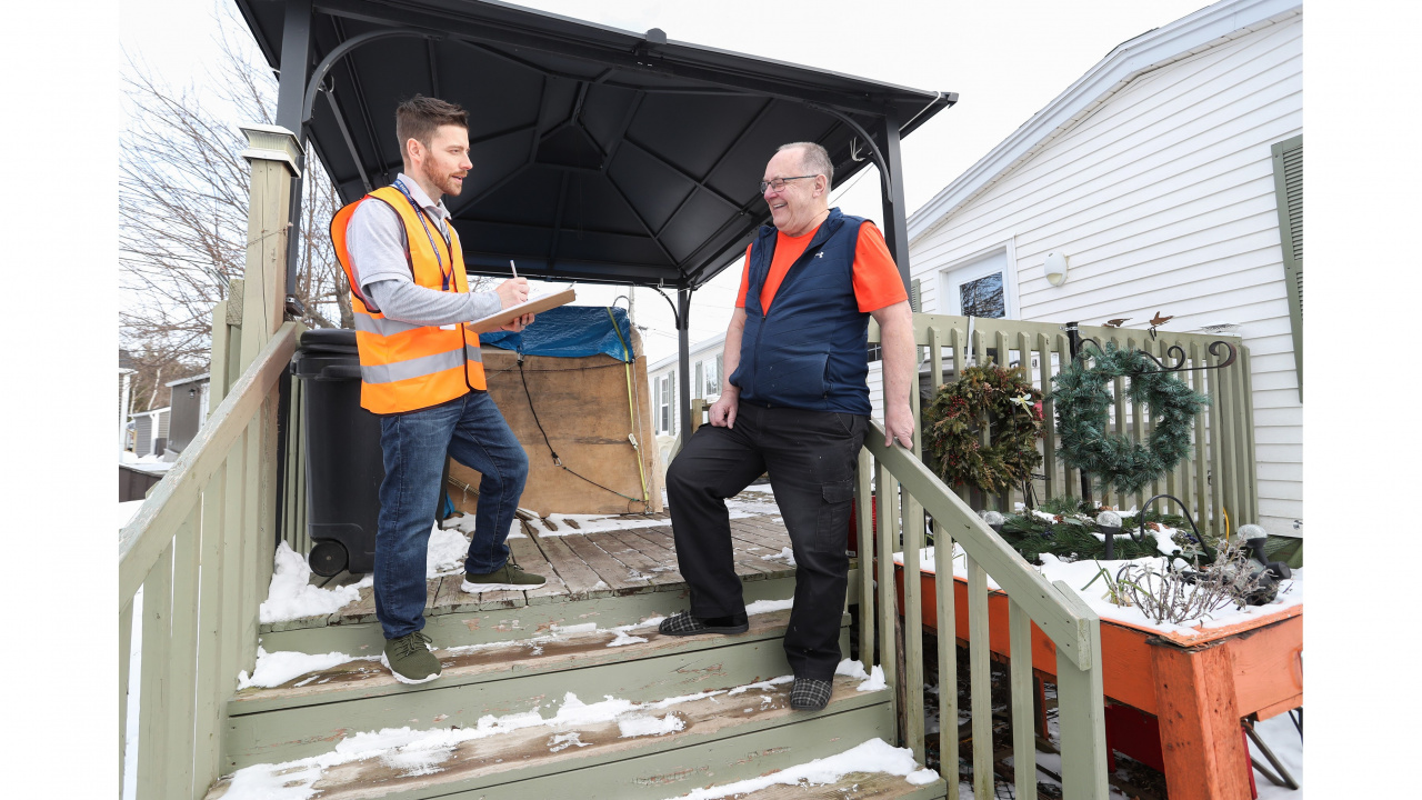 Photo of a handyman talking to a senior on exterior stairs