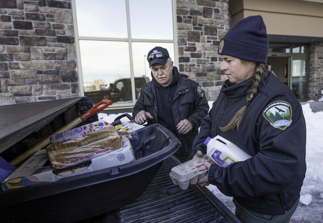 Department of Natural Resources and Renewables staff place grocery items into a snow sled.