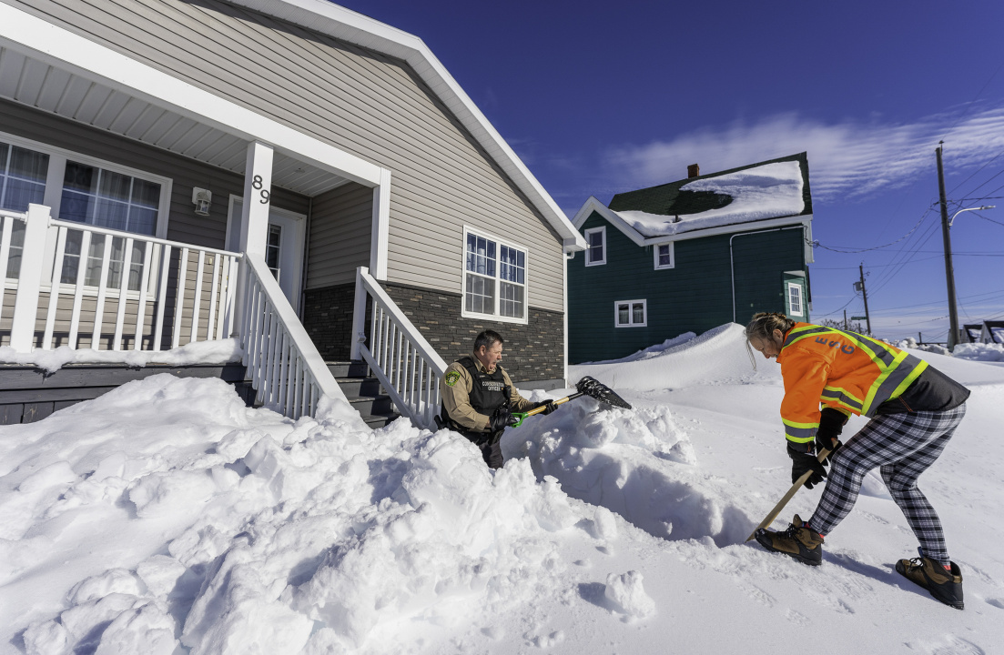 Department of Natural Resources and Renewables staff shovel out the entryway to a home.