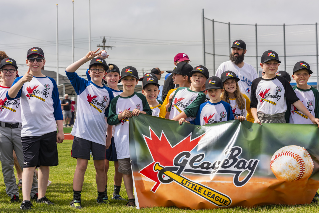 Photo of children wearing ball caps and Glace Bay team uniforms and holding banner that says Glace Bay Little League