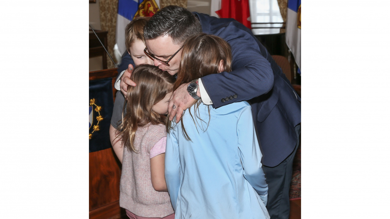 Photo of Community Services Minister Brendan Maguire hugging his three children.