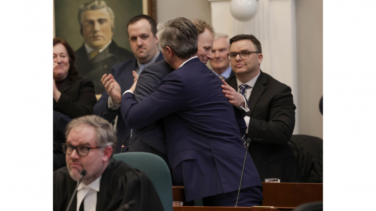 Finance and Treasury Board Minister Allan MacMaster embrace after the Minister's budget speech 