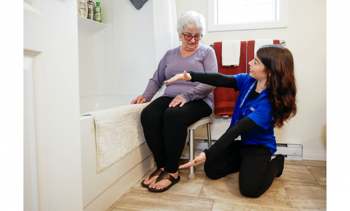 Photo of an occupational therapist with senior citizen beside a bathtub talking about home modifications