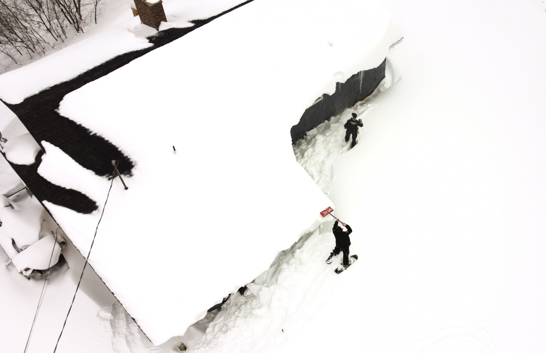 Aerial photo of two conservation officers on snowshoes outside a snow-covered house