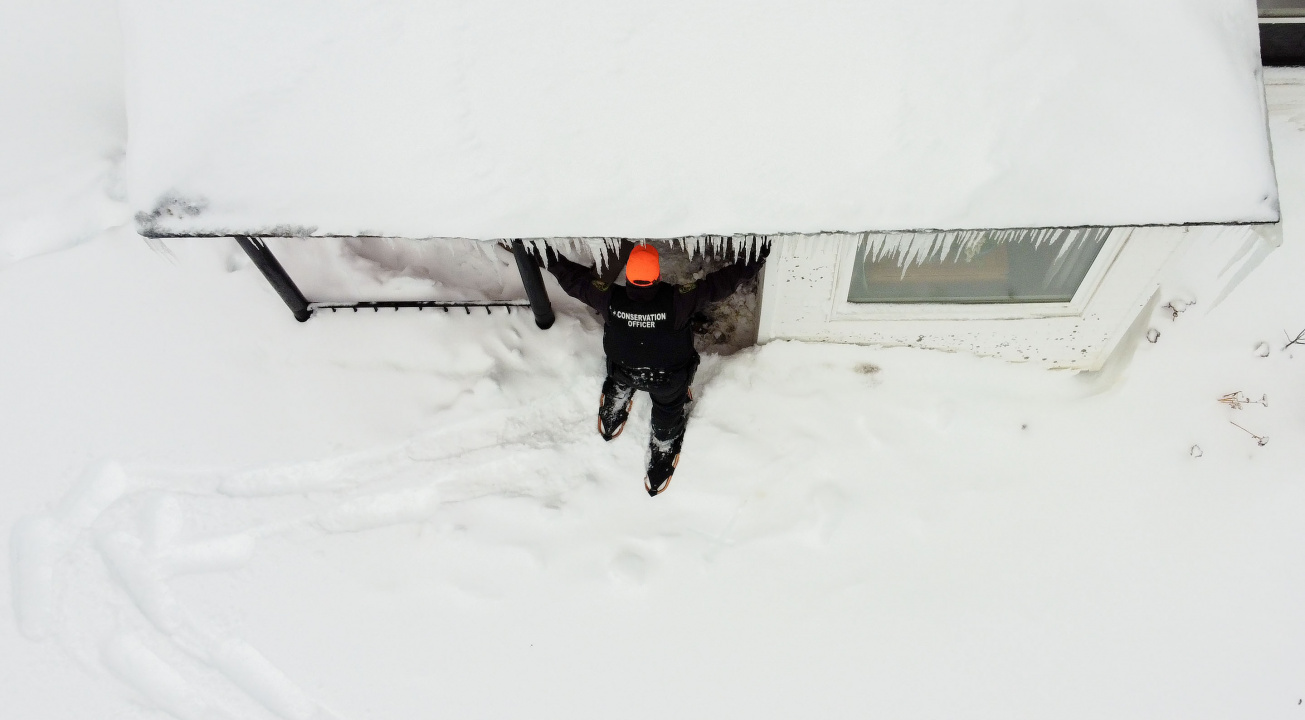 Aerial photo of conservation officer outside a snow-covered house