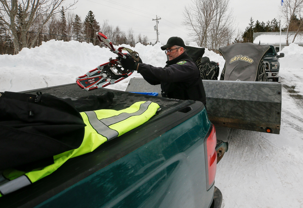 Photo of a conservation officer putting snowshoes on the back of a truck