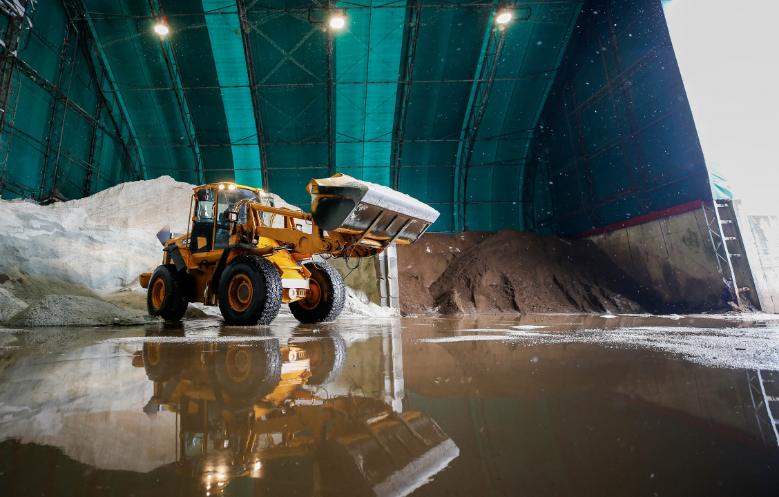 photo of a plow in front of a pile of snow inside a depot