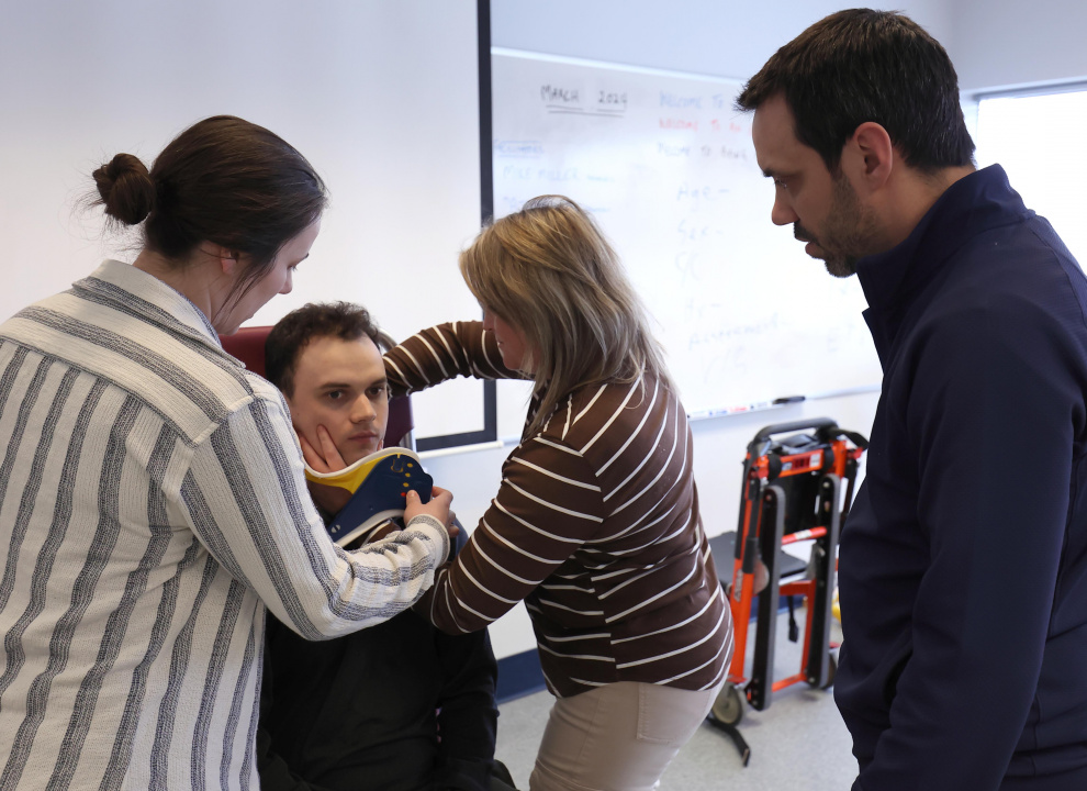 emergency medical responder learners practice putting on a neck brace.